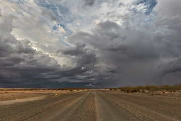 Gravel road with stormy sky, en route to the Namibia desert. Sossuvlei.