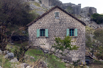 Fototapeta na wymiar old stone house in the mountains with green Windows with fortress