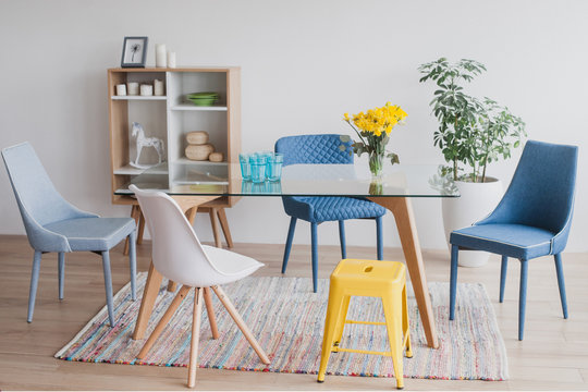 Simple design of dining room with colorful chairs and glass table