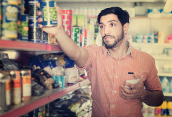 Guy customer with note choosing canned products
