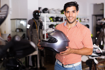 man who is choosing modern helmet for motorbike in the store.