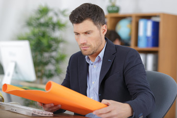 businessman opening roll of colored paper