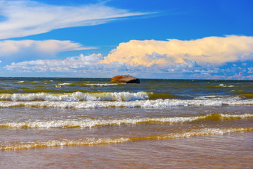 Waves, granite stone, evening clouds. Evening landscape on the Gulf of Finland.
