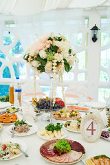 Table setting at luxury wedding reception. Beautiful flowers on wedding table. Number at table for guests on wedding banquet in restaurant hall