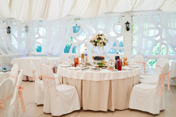 Wedding table setting and chairs for guests. Restaurant table set with food, cutlery and crockery for festive event. Catering service. Wedding reception. Table arrangement