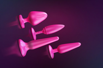 a collection of different types of sextoys, including dildo, vibrators and butt plugs over a dark...
