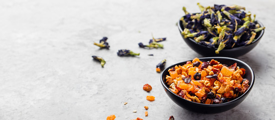 Fruit, herbal and flower tea in bowls. Grey stone background. Copy space