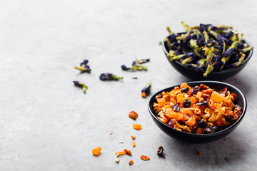 Fruit, herbal and flower tea in bowls. Grey stone background. Copy space