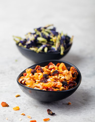 Fruit, herbal and flower tea in bowls. Grey stone background.