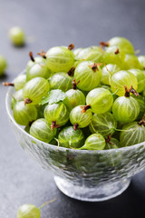 Gooseberries in glass bowl on black stone slate background.