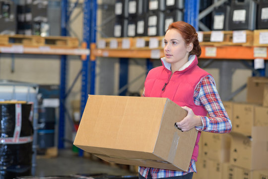 female worker carrying a box in warehouse