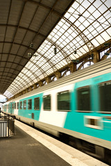 Fototapeta na wymiar Moving white turquoise train leaving train station