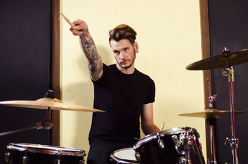 Tattooed drummer performing, pointing with drumstick 