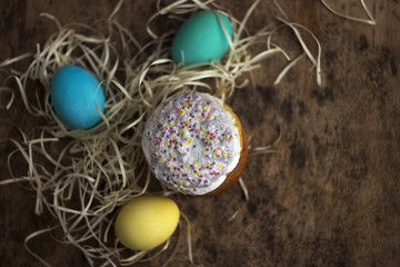 Easter cake and colourful Easter eggs on a wooden table in a wicker box, a religious holiday