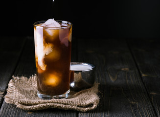 Iced coffee in a tall glass on jute background.