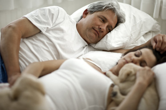 Mature man looking at her partner while sleeping on bed