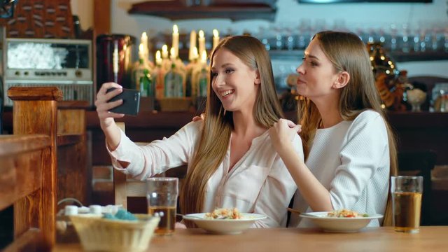 Two beautiful women taking selfie in cafe