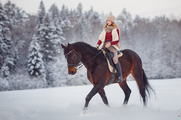 Horse. Girl rider rides brown horse through winter forest in snow. Concept preparation for...