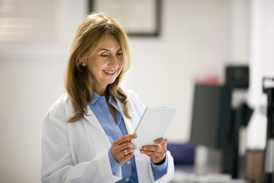 Smiling mid adult doctor using a digital tablet in hospital