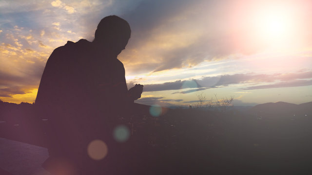 Silhouette Of Young Muslim Man Praying During Sunset