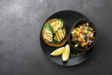 Toast with zucchini grill and salad of olives, cucumbers, tomato, sweet red onion, yellow chili pepper with grilled chicken breast. Top View.
