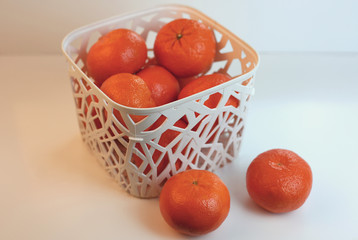 White basket with fruits. Mandarins, oranges in a wicker basket