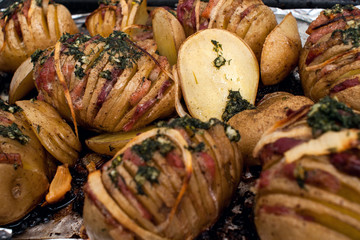 Potato.Roasts potatoes. Home cooking. Baking pan full of baked potatoes stuffed with bacon sausage onions and grated cheese flavored with caraway seeds salt pepper and fresh herbs parsley and dill