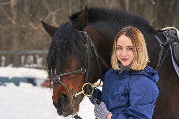 Portrait of a young girl with white hair next to a brown horse. The girl holds the horse and...