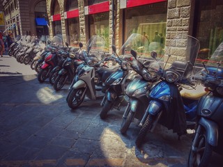Obraz premium Rząd zaparkowanych skuterów przy ulicy