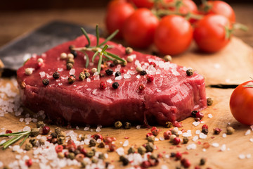 Raw beef steak on a dark wooden table.
