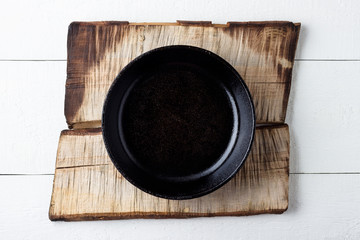 Cooking background concept. Empty rustic black cast iron plate over wooden background.
