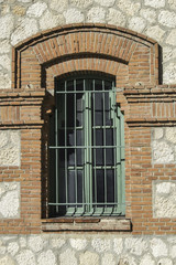Fototapeta na wymiar ventana con reja verde y marco de ladrillo.