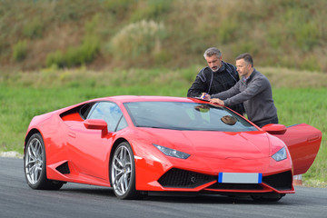 two men stood by sports car