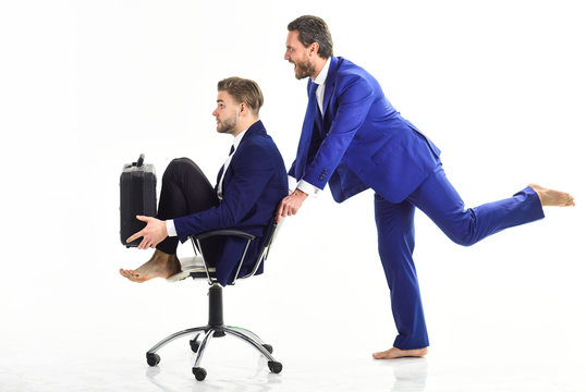 Man in suit pushing chair with colegue on.