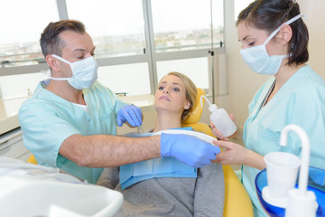 Dentist preparing to treat young lady