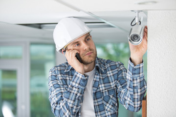 male professional cctv technician using the phone while working