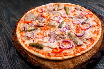 Delicious pizza with meat, onions, gherkins and chili pepper close up. Italian food, restaurant menu