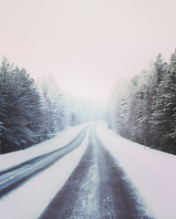 Obraz premium Wintry road, curve ahead. Snowy ground and forest. Image has a vintage effect applied.