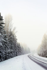 Wintry road, curve ahead. Snowy ground and forest. Image has a vintage effect applied.