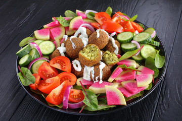falafel balls on black plate with salad