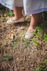Girl's feet in earthy soil with wild grass.