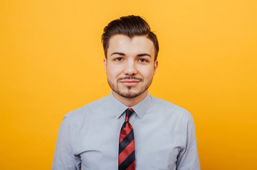 Portrait of handsome young man looking confident at the camera over yellow background
