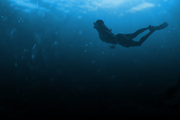 Fashionable and athletic girl diver alone in the depths of the ocean.