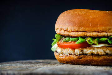 homemade appetizing chickenburger on dark background with copy space