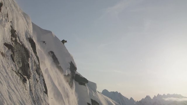 Skier jumps off side of mountain, slow motion