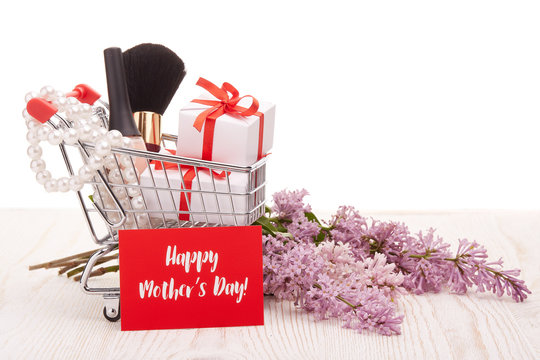 Lilac flowers and gifts on shopping trolley.