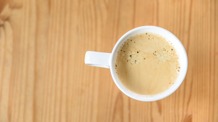 Kaffee in einer weißen Tasse auf einem Holztisch