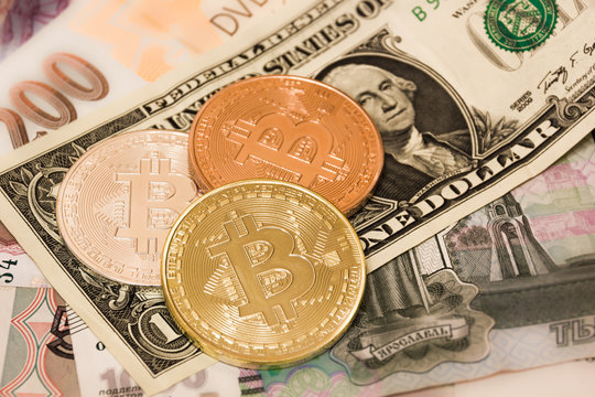 Symbolic coins of bitcoin on banknotes of US dollars, czech crowns and Russian rubles.
