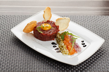 Gourmet tartare, toasted bread and salad on a plate.