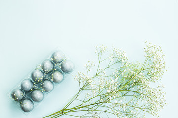 Delicate blue Easter eggs among the flowers of gypsophila on a blue background. Copyspace